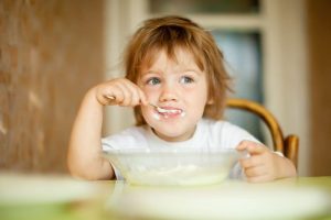 child eats with spoon in home